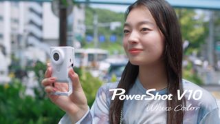 A Canon PowerShot V10 White, being held by a young woman outdoors