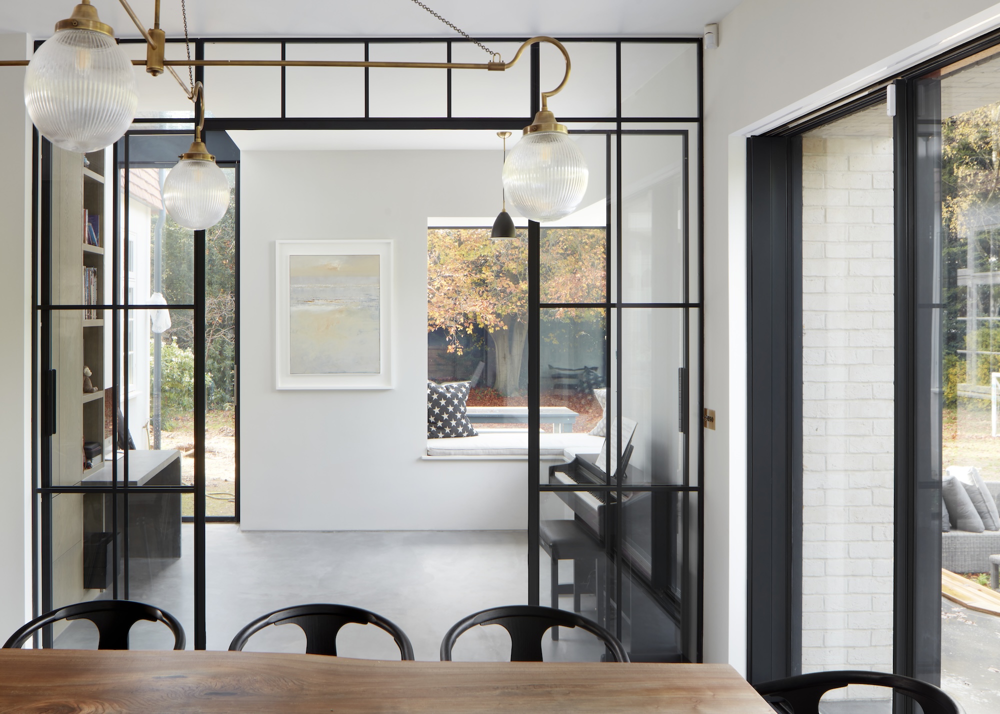 A simple white living space with Crittall-style doors between two spaces