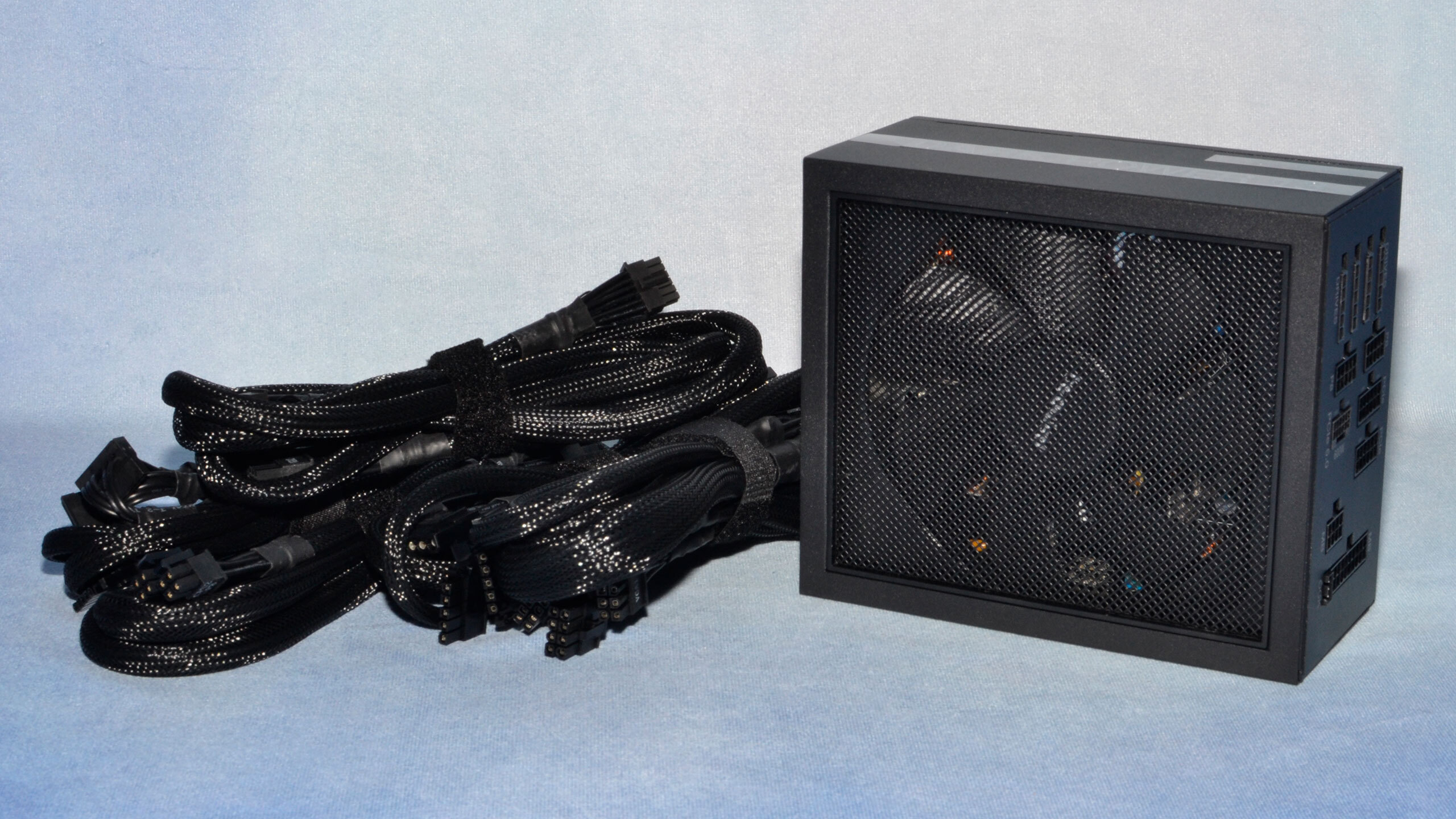 A black be quiet! PSU with cables on a light blue background.