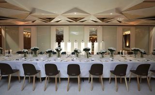 Long dining table and chairs with candle holders and flowers