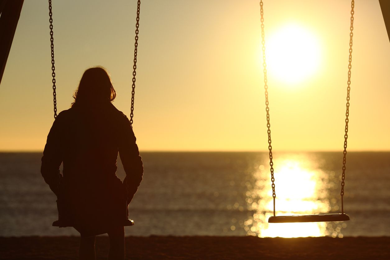 A woman sitting alone on a swing.