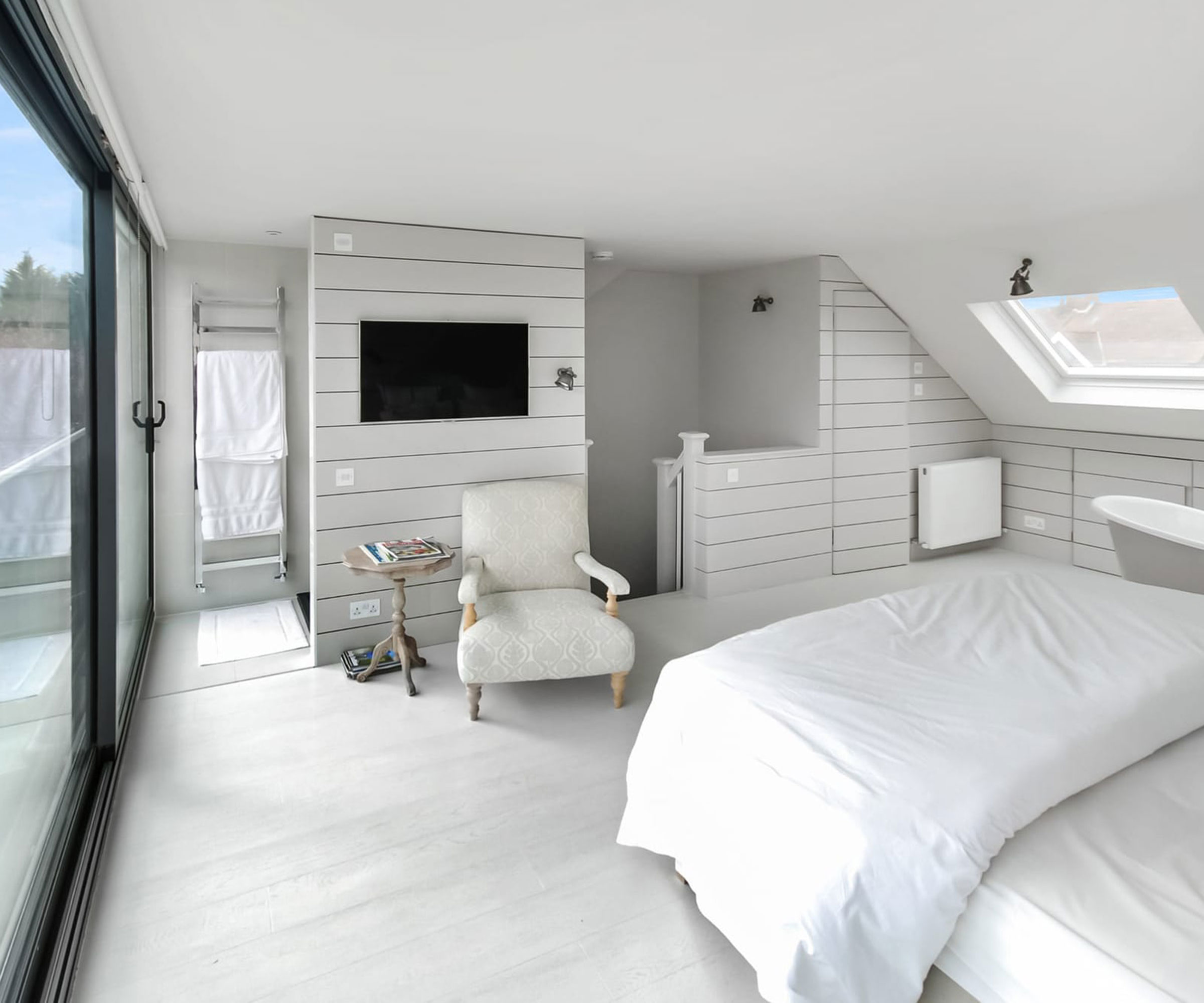 white loft bedroom with freestanding bath