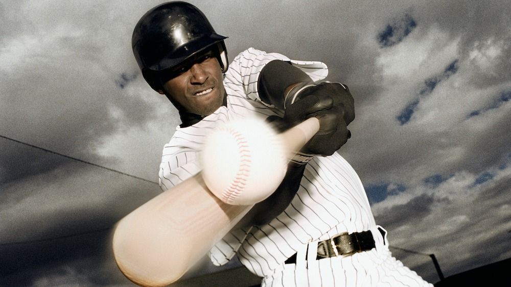 A baseball player hits a baseball during a game. 