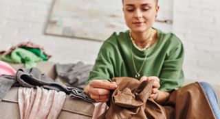 Woman sitting on a sofa decluttering clothing