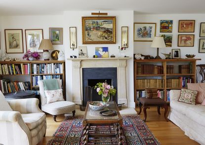 living room with white walls and lots of art and antiques highlighted by lighting