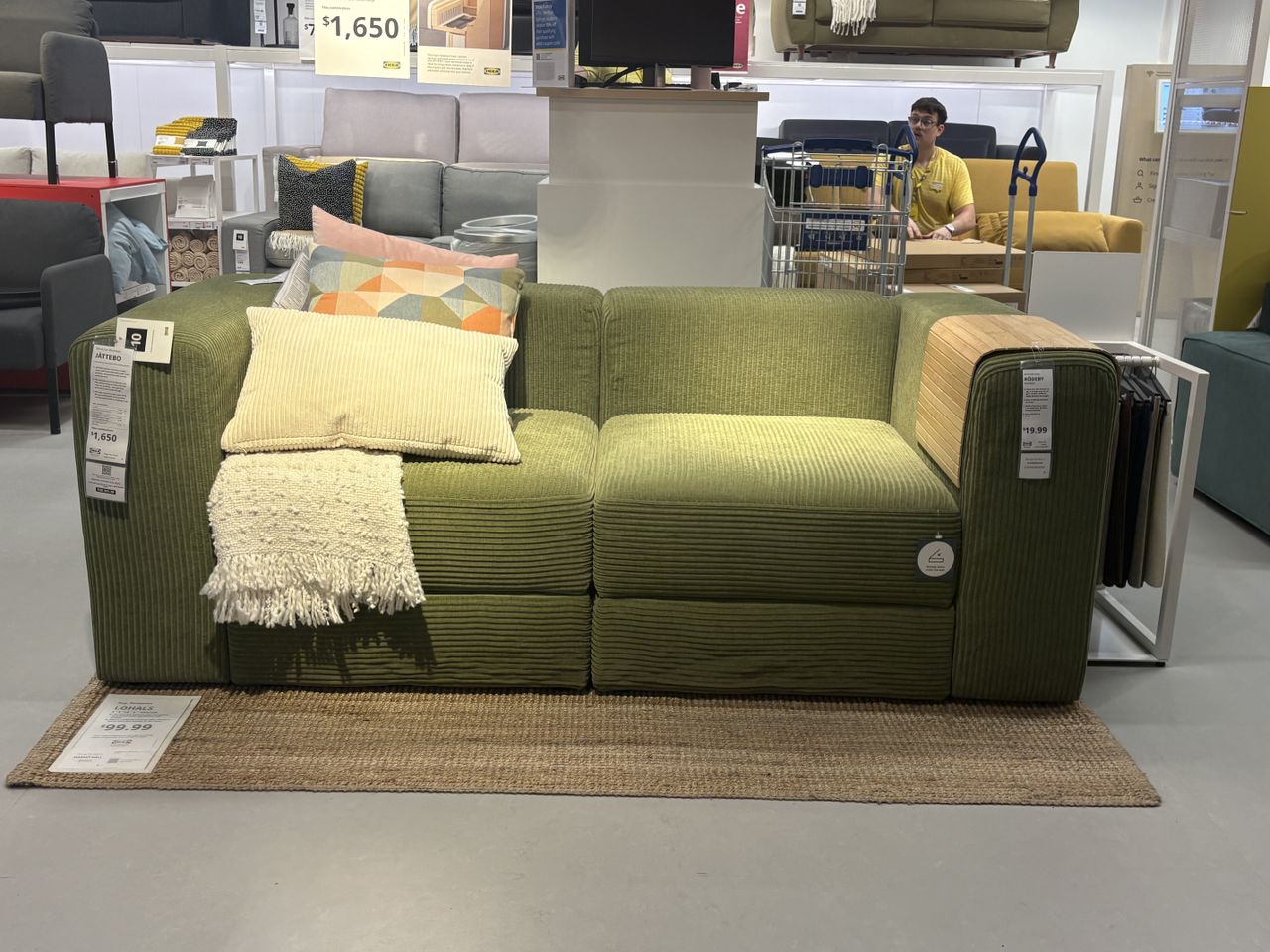 a low profile green couch with pillows sitting in a showroom.