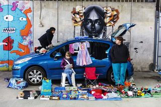 Family at a car boot sale in front of fencing adorned with stylish graffiti murals
