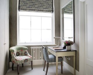 small home office with desk, chair, large window, wallpapered walls, wardrobes with matching print