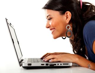 A woman looks at her laptop and smiles