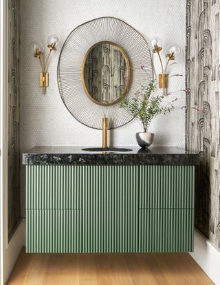 Bathroom with green ribbed vanity unit, brass wall light and brass mirror