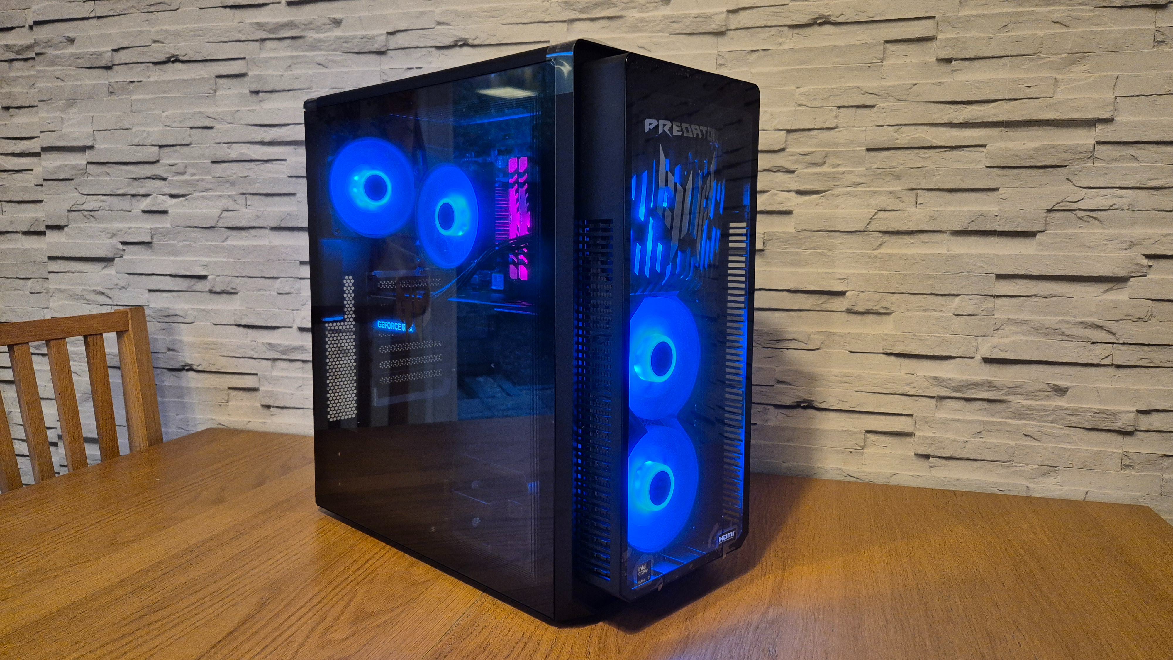 An Acer Predator Orion 5000 gaming PC sitting on top of a wooden surface infront of a white brick effect wall