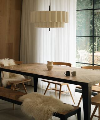 winter decor ideas, dining room with sheepskins on bench and chair, sculptural pendant light, earthenware, pleated drape at crittall doors