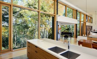 The piano in the main living space sits within its own glazed alcove, a triangle-shaped space that juts out into the woodland