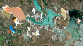 A satellite photo of roughly a dozen brightly colored lagoons