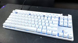 The Logitech G PRO X TKL Rapid gaming keyboard in white on a black desk mat with blue RGB