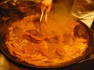 Tripe stew being cooked in a large, shallow pan