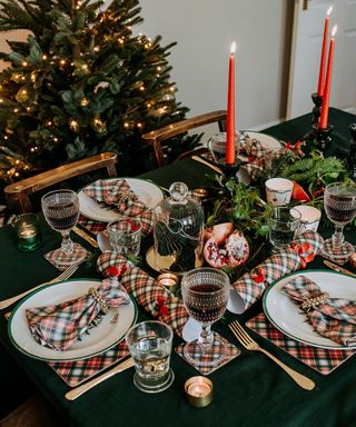 Christmas tablescape with red and green decor and Christmas tree in background