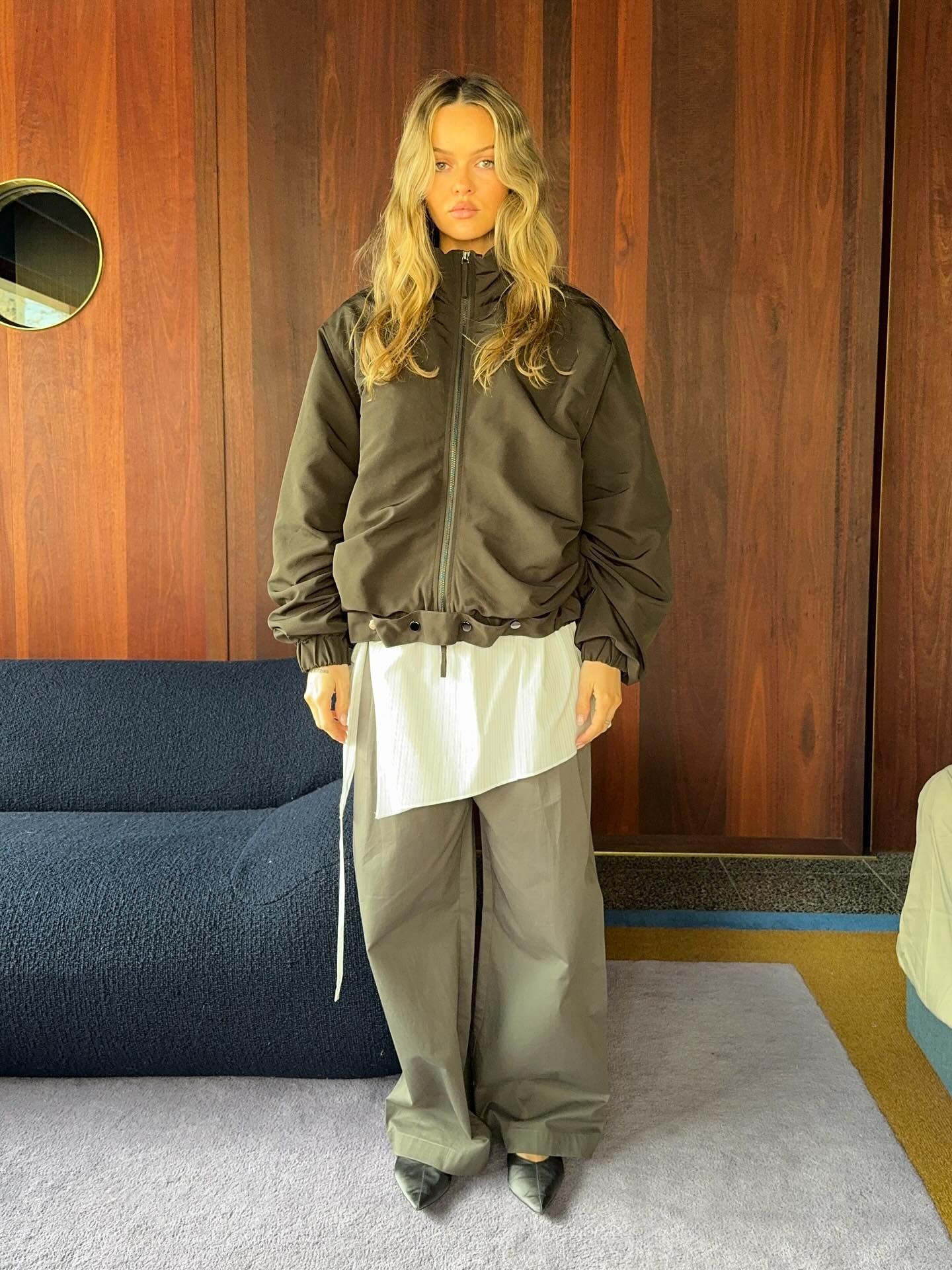 Paris wears a sport jacket, white long shirt, khaki pants, and black pointed toe shoes.