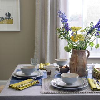 Laid dining table with dinnerware and vase of flowers