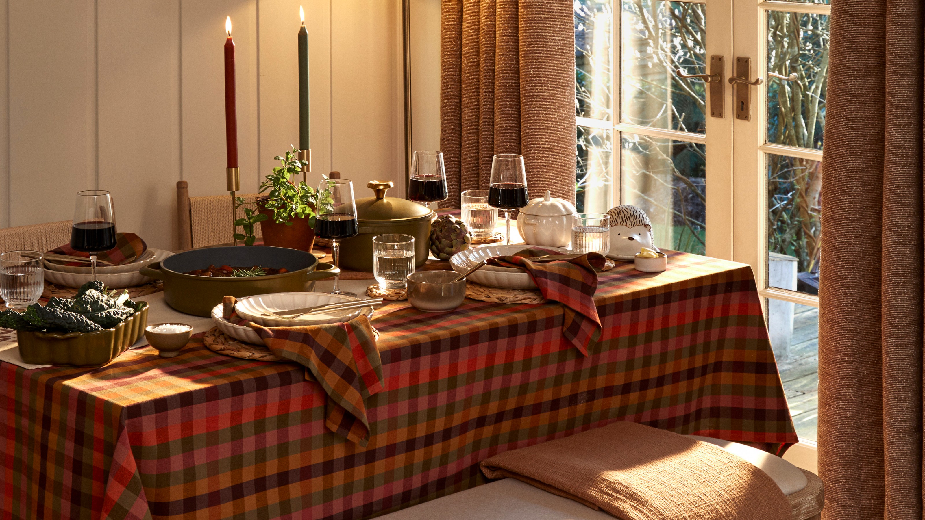 A set dining table with an autumn theme dressed with a multicoloured gingham tablecloth and matching napkins