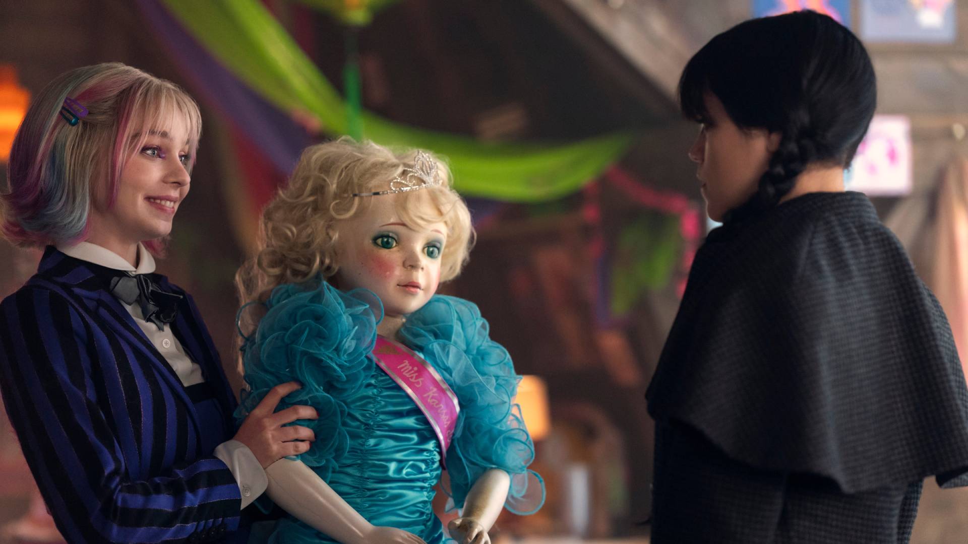 Wednesday (Jenna Ortega) and Enid (Emma Myers) holding a doll