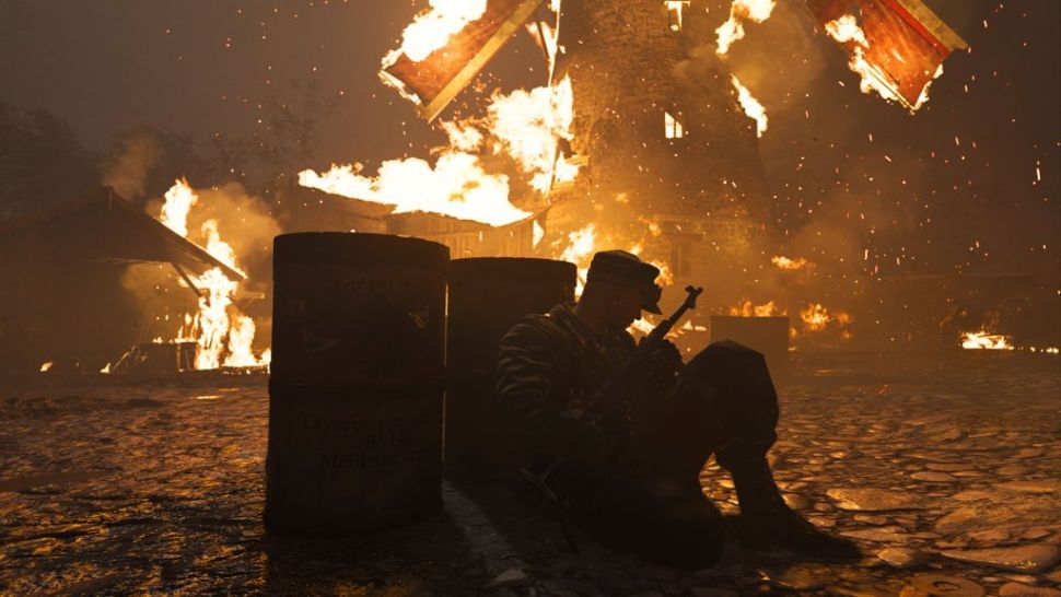 Soldier crouched behind barrels in front of explosion