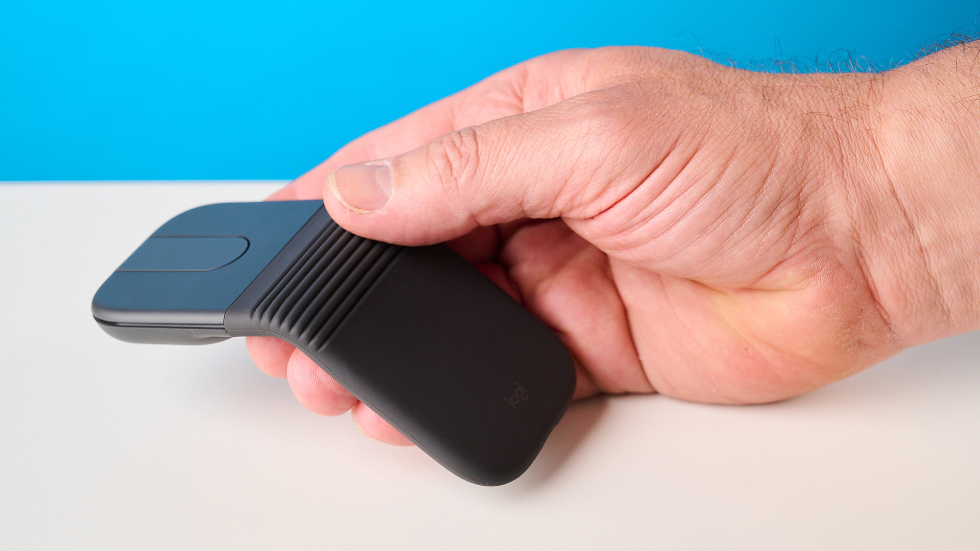 Logitech Mobi Fold mouse in graphite photographed in front of a blue background