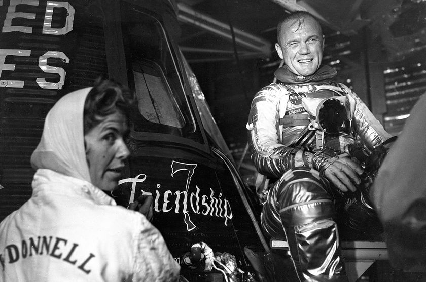 Artist Cece Bibby (at left) puts the final touches on the Friendship 7 logo as astronaut John Glenn looks on in approval.