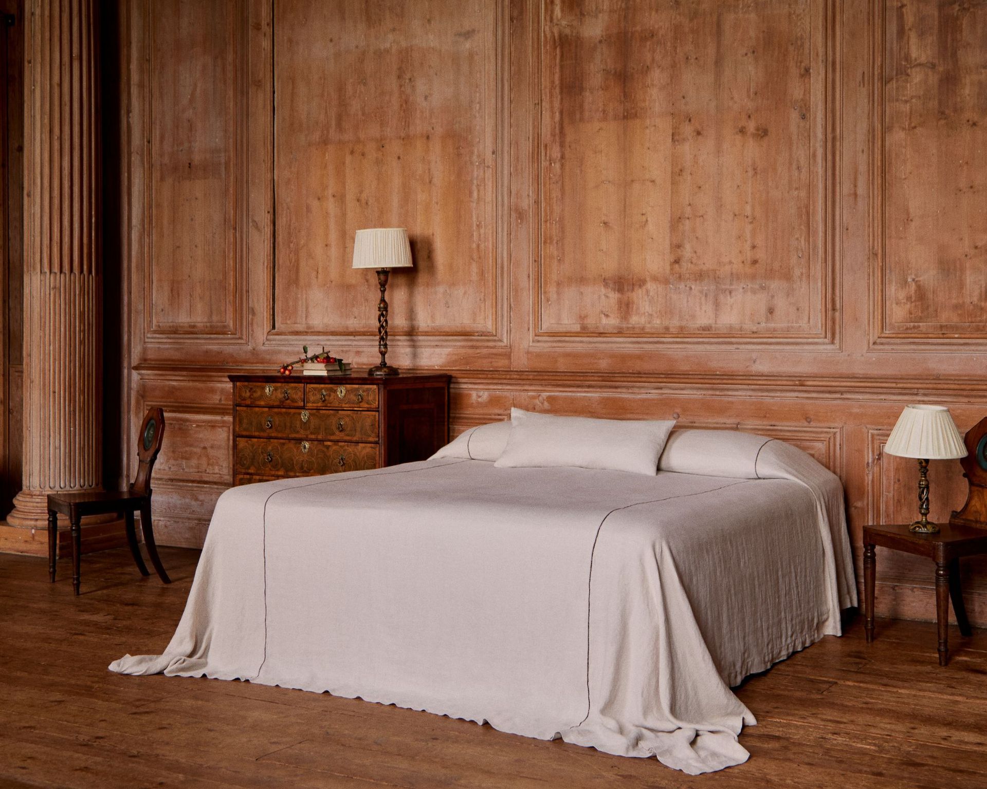 minimal bedroom with oversized white bedding and wooden walls and nightstands