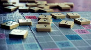 the best board games for two players – a Scrabble board with a random assortment of pieces up close
