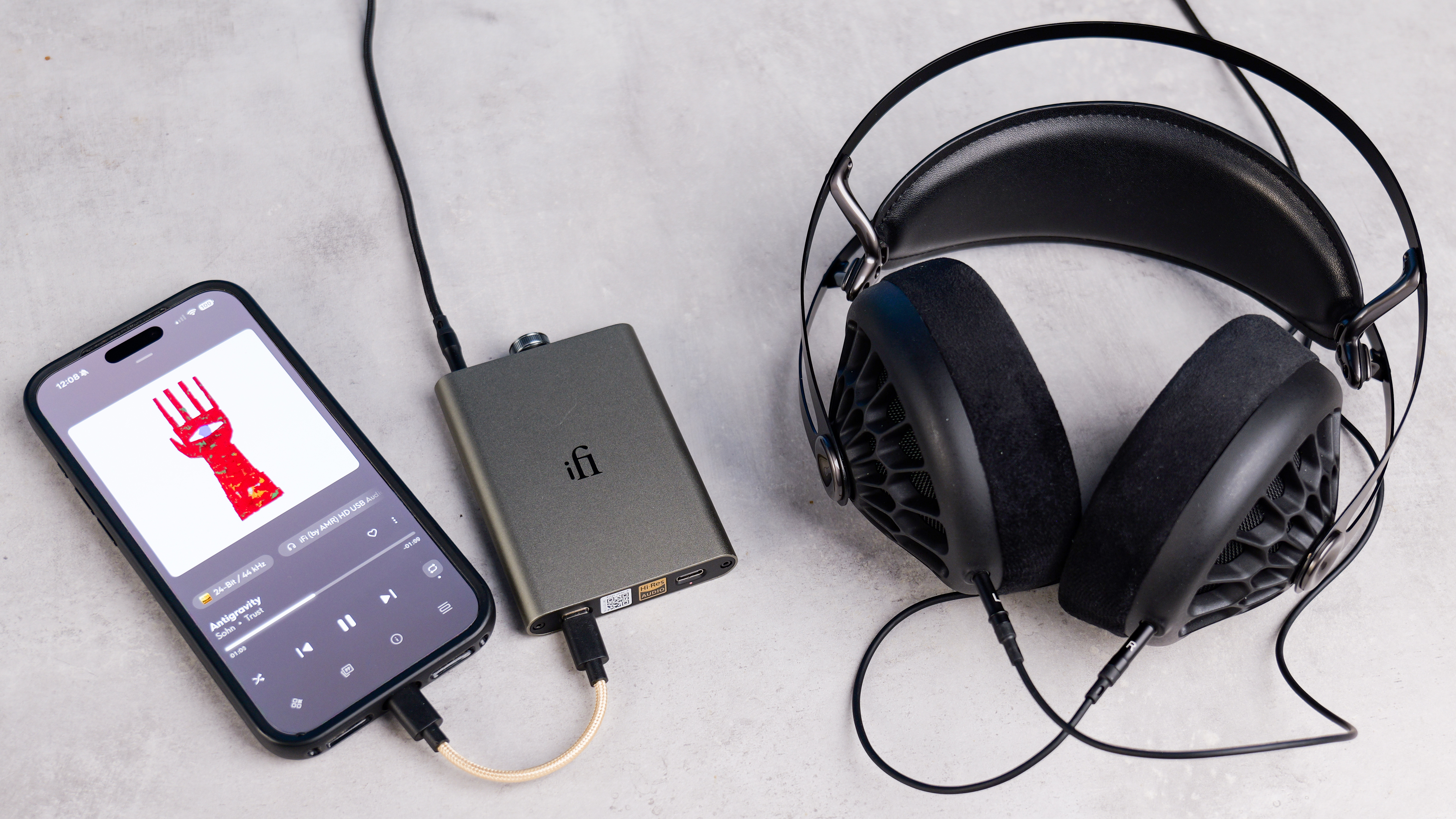 An iPhone playing a song while connected to the iFi hip dac 3 and the Meze 105 AER on a stone surface