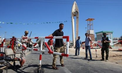Libyan rebel fighters stand guard at the entrance to the Zawiyah oil refinery after seizing control earlier this month: Experts say Gadhafi's fall will likely cause oil prices to drop.