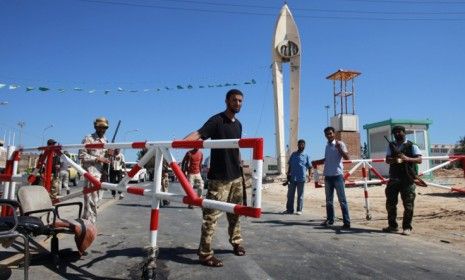 Libyan rebel fighters stand guard at the entrance to the Zawiyah oil refinery after seizing control earlier this month: Experts say Gadhafi&amp;#039;s fall will likely cause oil prices to drop.