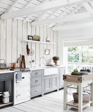 A small kitchen with grey cabinets, butcher's block, butler's sink, belfast sink, a slim Aga, range cooker in a rustic, country style