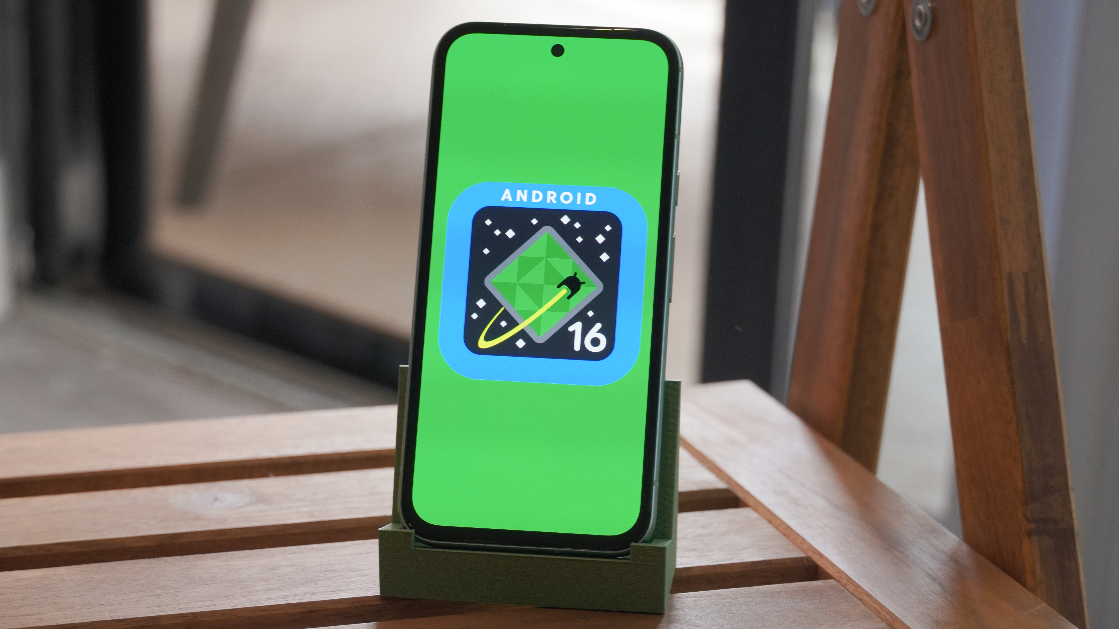 The Android 16 logo on a Google Pixel 8a outdoors.