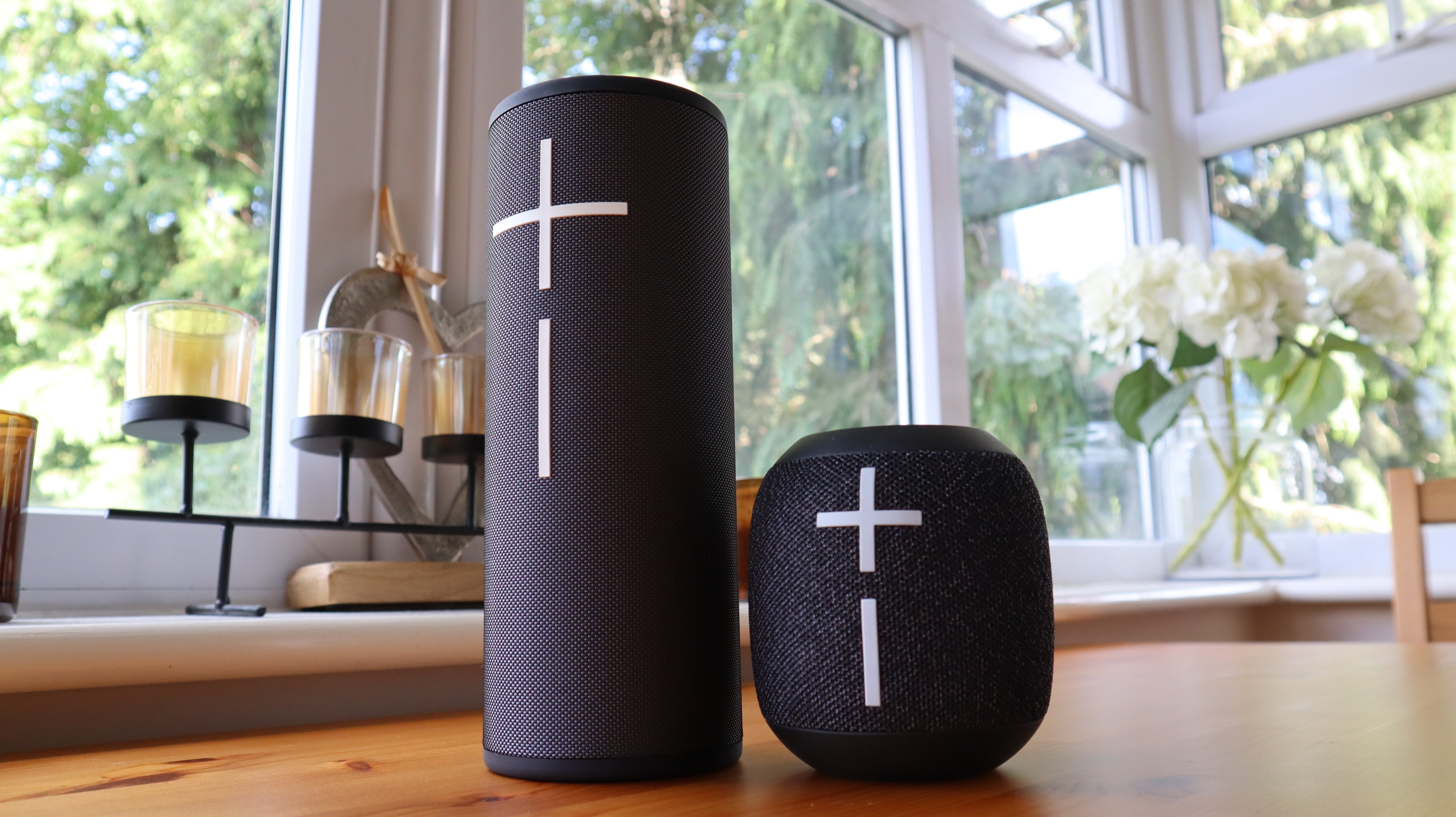 Ultimate Ears Megaboom 4 in black, in a house with white window frames in the background