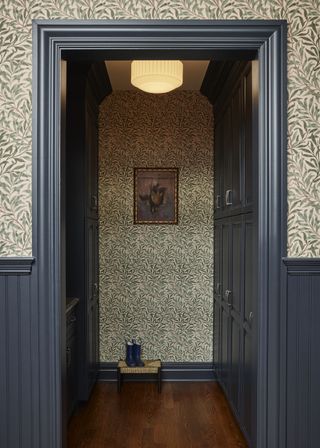 A mudroom with dark trim and floral wallpaper