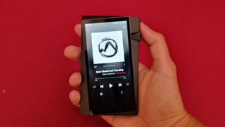 Astell & Kern A&norma SR35 player in the hand against a red wall background