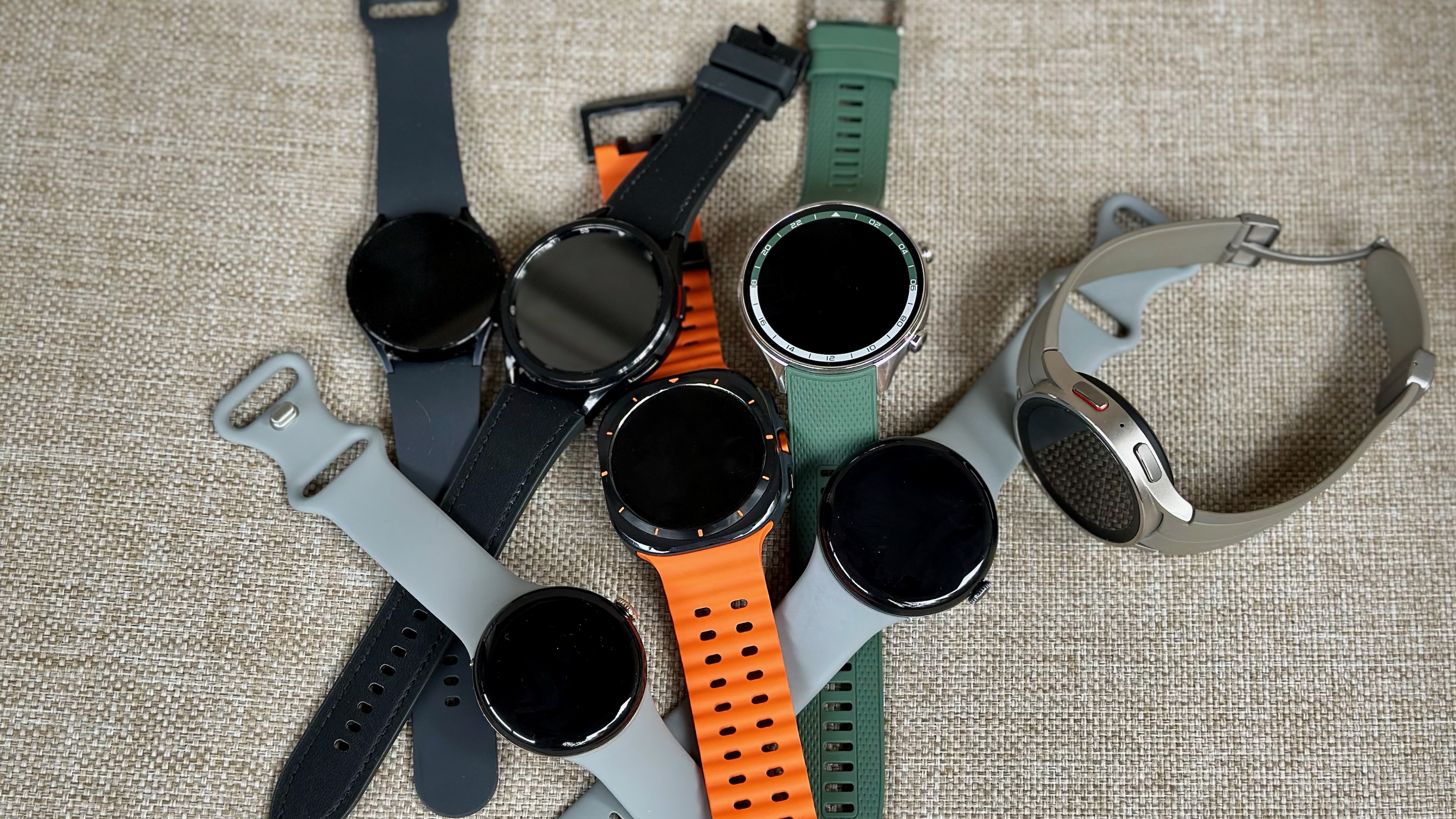 A bunch of Wear OS watches: Samsung Galaxy Watch Ultra, 6, 6 Classic, and 5 Pro; Google Pixel Watch 3 and 2; and OnePlus Watch 2R.