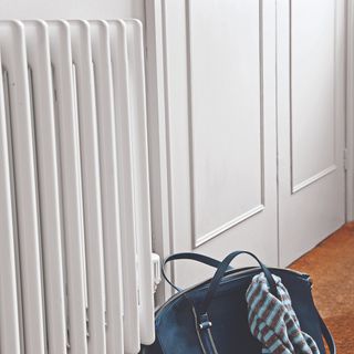 A hallway with a white radiator and a handbag on the floor