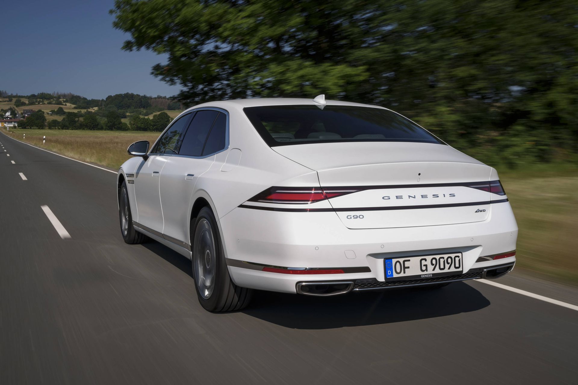 Genesis G90 from rear, on road in sunshine