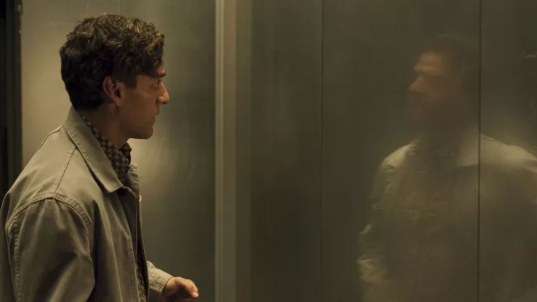 Oscar Isaac looking at a reflection of himself in a door in Moon Knight