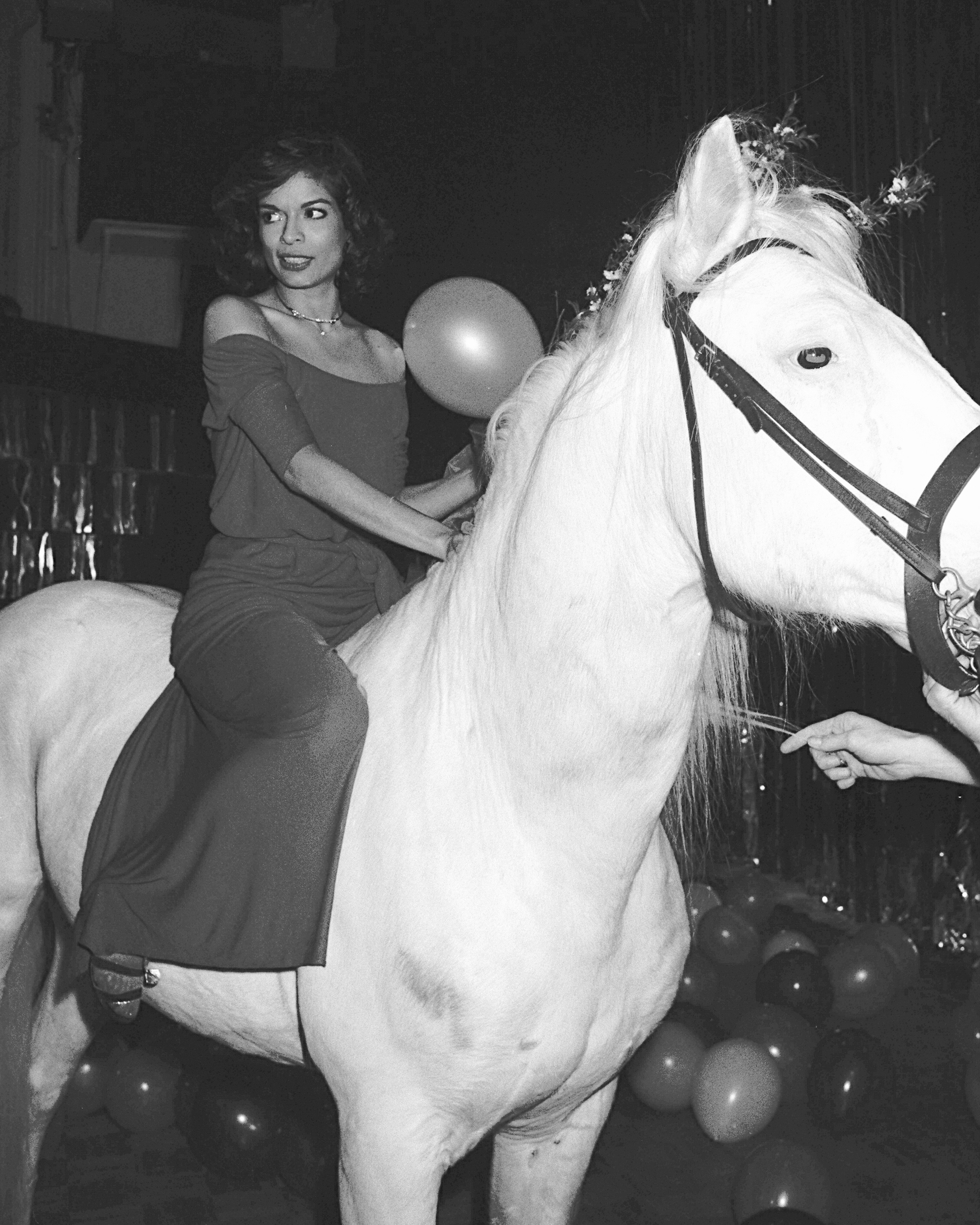 An image of Bianca Jagger wearing Manolo Blahnik shoes while riding a horse through Studio 54.