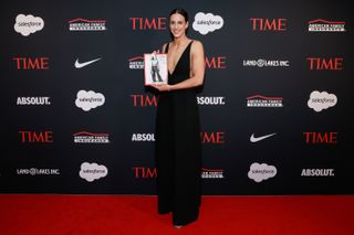 Caitlin Clark wearing a black jumpsuit and holding a magazine on the TIME red carpet