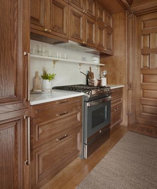 Kitchen with mid-toned wood cabinets on floor and wall, range, and stone splashback