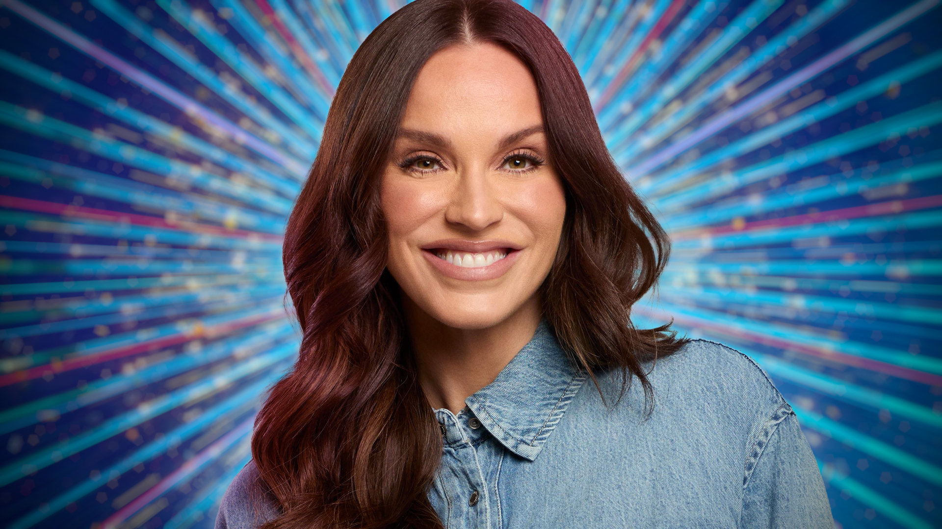 Vicky Pattison smiling for the camera with a glittery blue background behind him