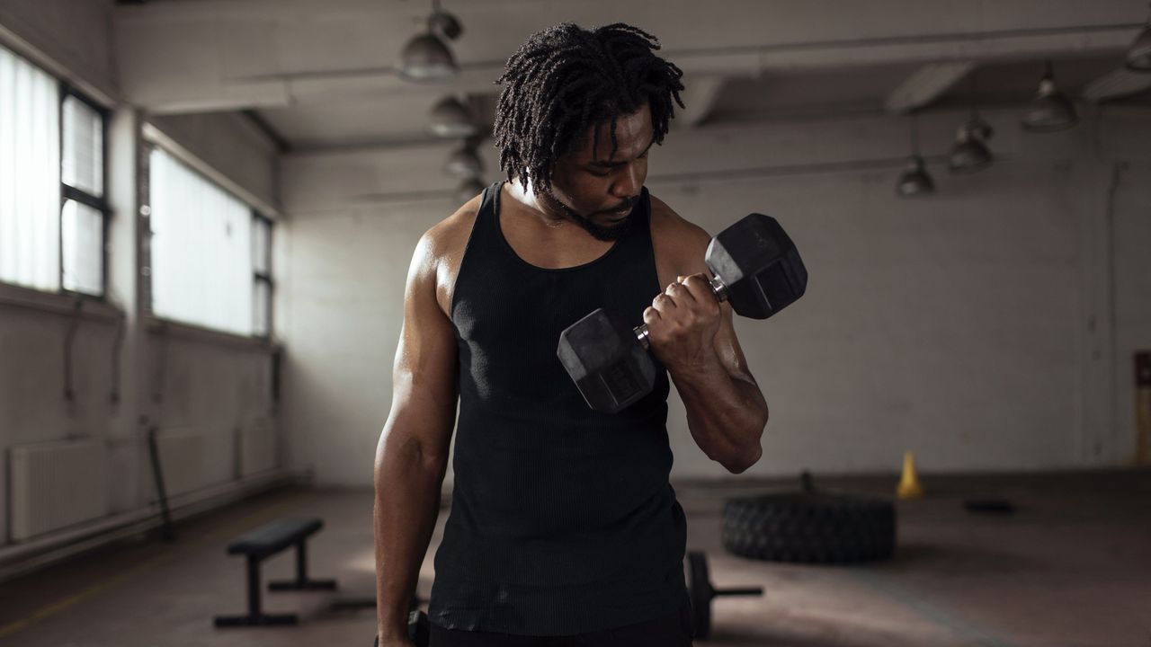 Man doing bicep curl with dumbbell in a gym