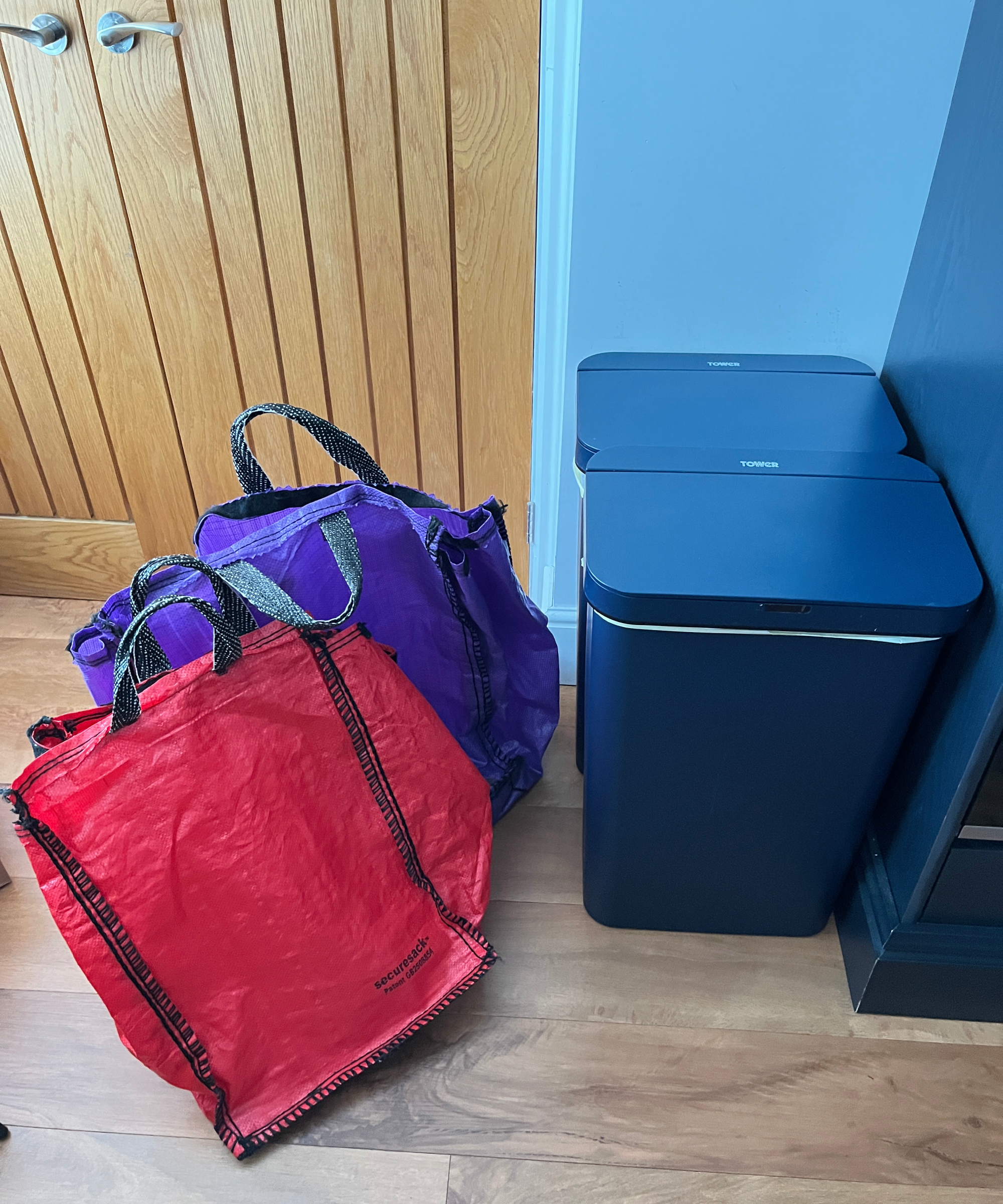 large red and purple recycling bags next to navy kitchen bins