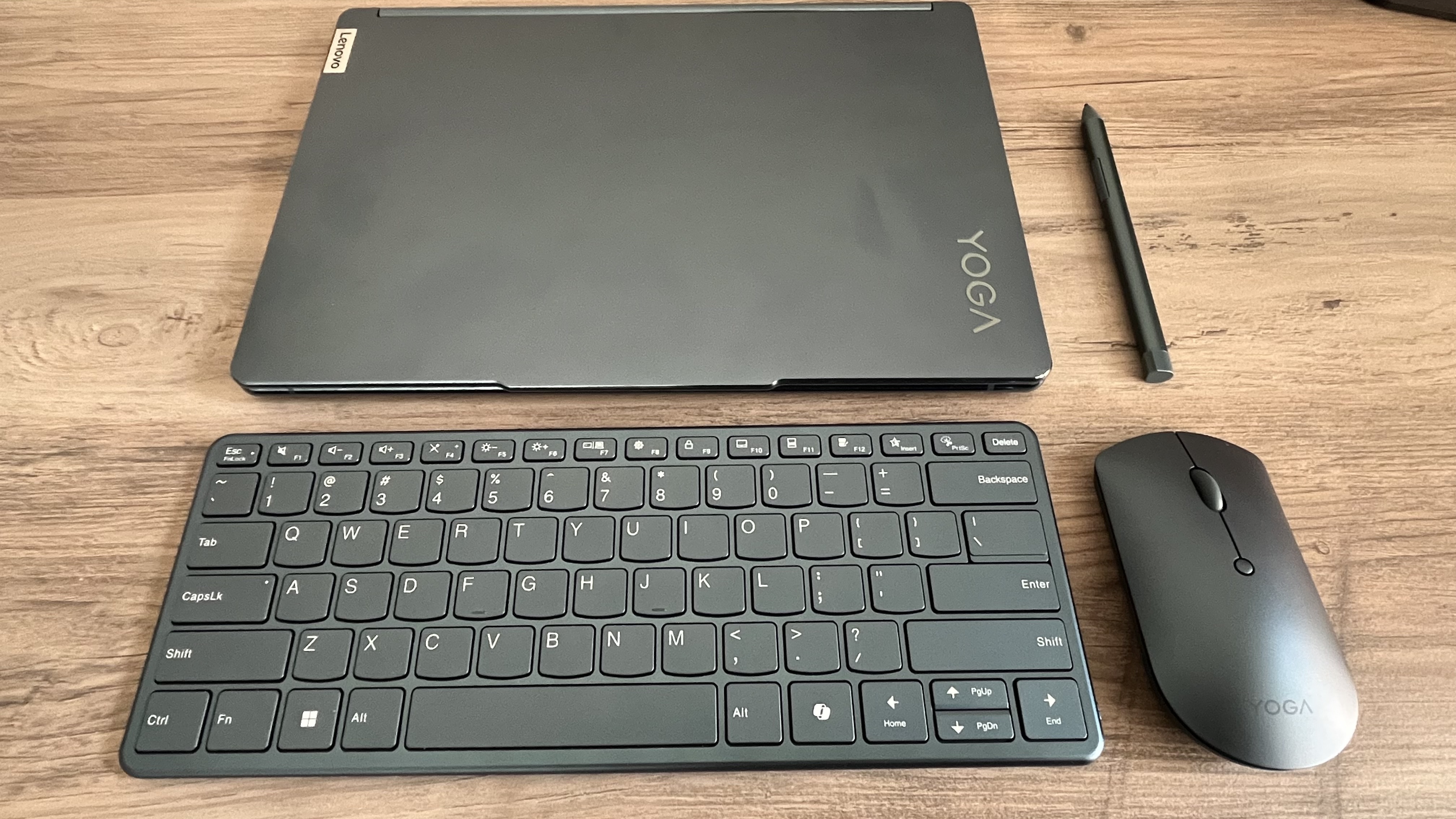 Lenovo Yoga Book 9i laptop, closed, next to its Bluetooth accessories