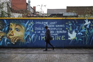 Person walking in front of a graffiti wall taken on the Leica SL3-S with a Leica Summilux SL 50mm f/1.4 Asph lens